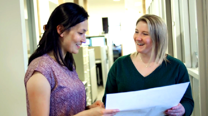 Two co-workers having a conversation in an office setting.