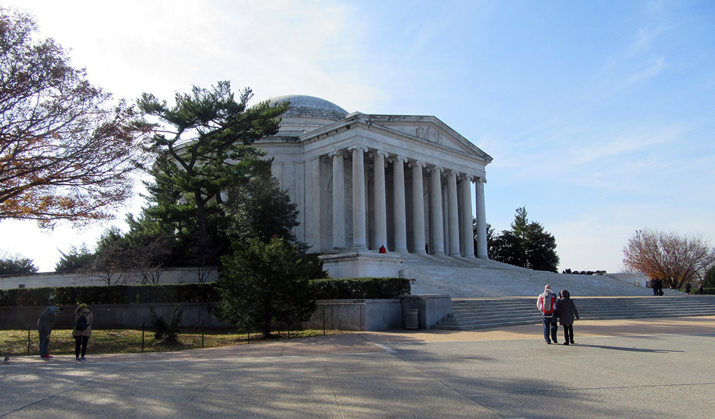 Pedestrians stand in front of the staircase and front entrance to the Thomas Jefferson Memorial in Washington, DC.