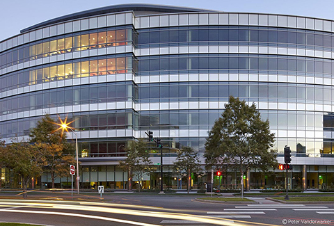 The curved glass wall office building at 300 Binney Street in Cambridge, Massachusetts is pictured at dusk.