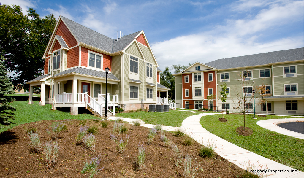 Green lawns in front of a red and grey apartment building. 