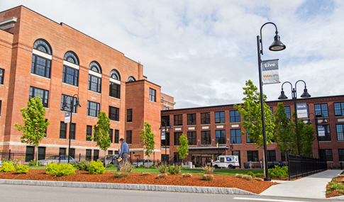 A man walks on the sidewalk past the courtyard entrance at Volk Lofts in Worcester, Massachusetts.