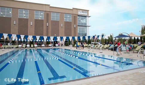 People walk around the swimming pool outside Life Time Fitness Framingham.