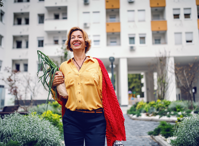 A woman carries greenery in a walkable community.