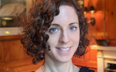 Anne-Elizabeth wearing a navy shirt in a wood-paneled room.