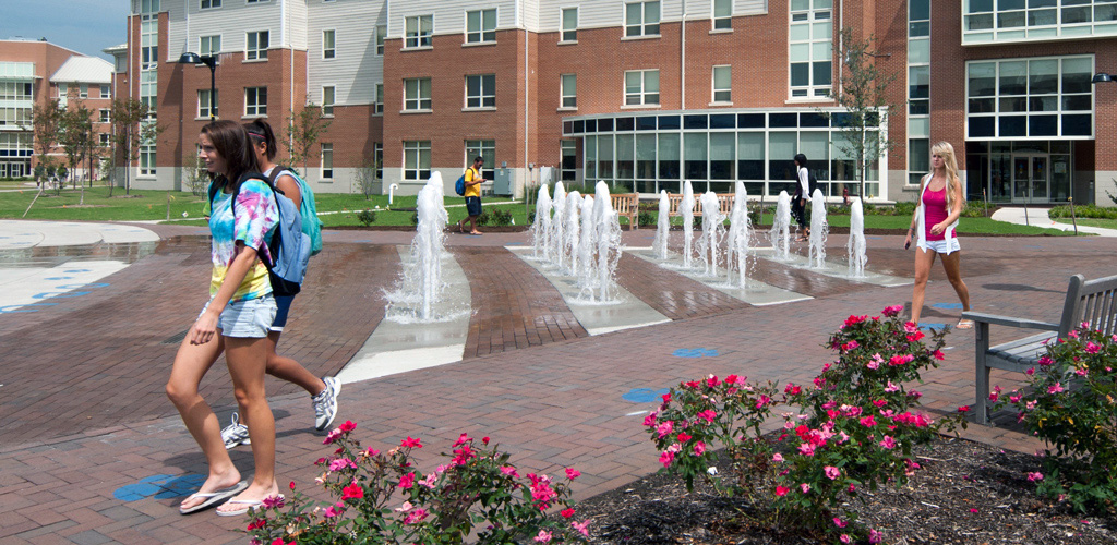 Students pass a water feature as they walk through Old Dominion University’s Campus on a sunny day  