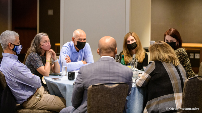 A group of men and women in discussion around a table.