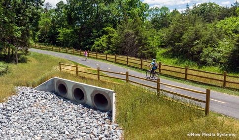 One bike rider and one runner use a section of the trail built across a culvert.