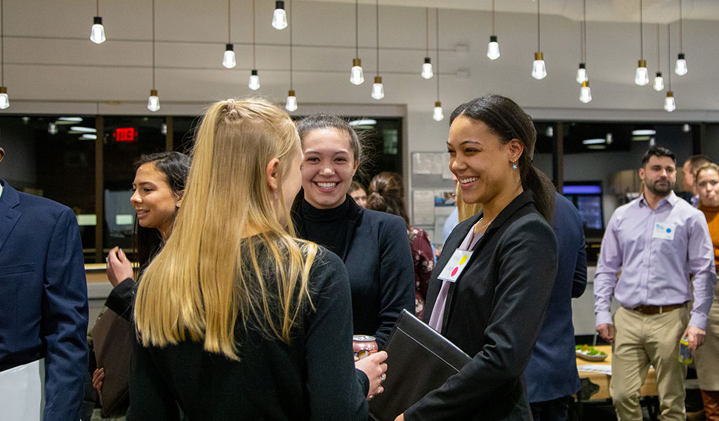 VHB employee engages with two students at a college open house recruiting event.