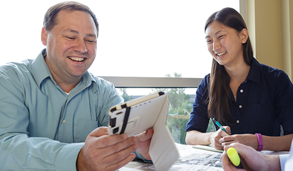 VHB employees engaged during a meeting while reviewing plans and a tablet.