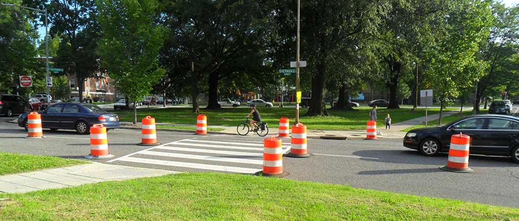 A suburban street with designated bike lanes marked by orange barrels.