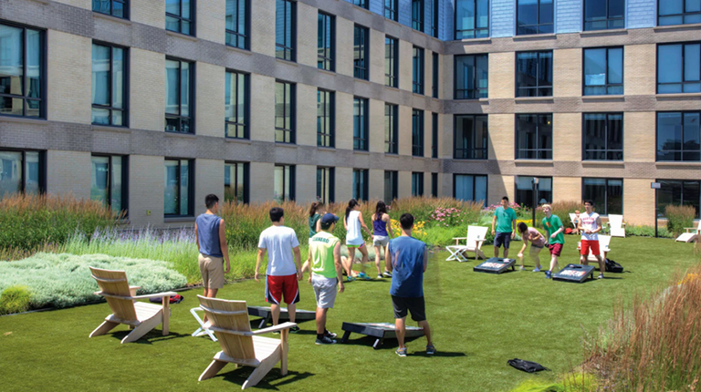 A group of friends playing cornhole outside there apartment building