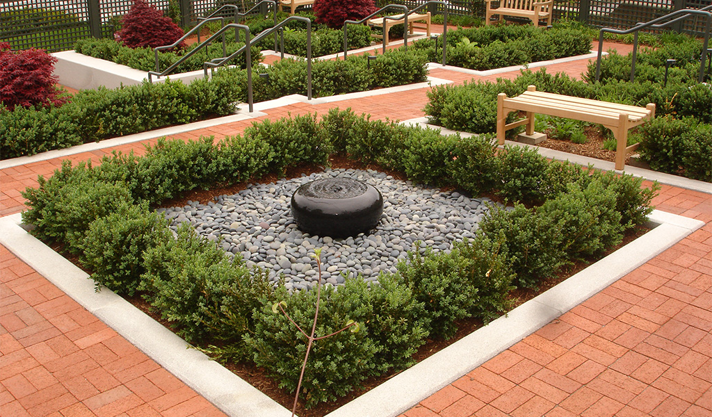 Outdoor garden with brick walkways and water feature.